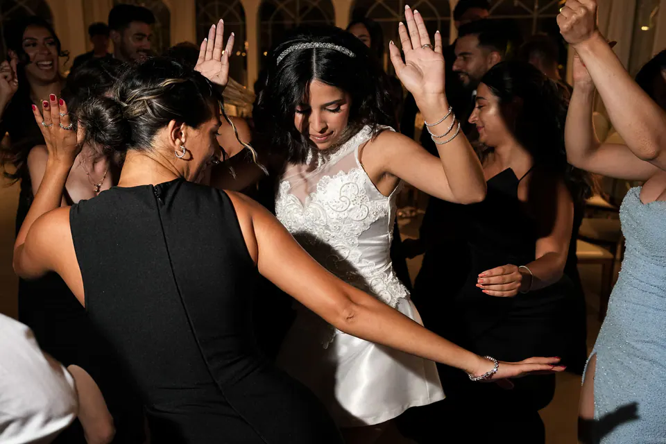 La mariée danse avec ses amies en robe noire, les mains levées.
