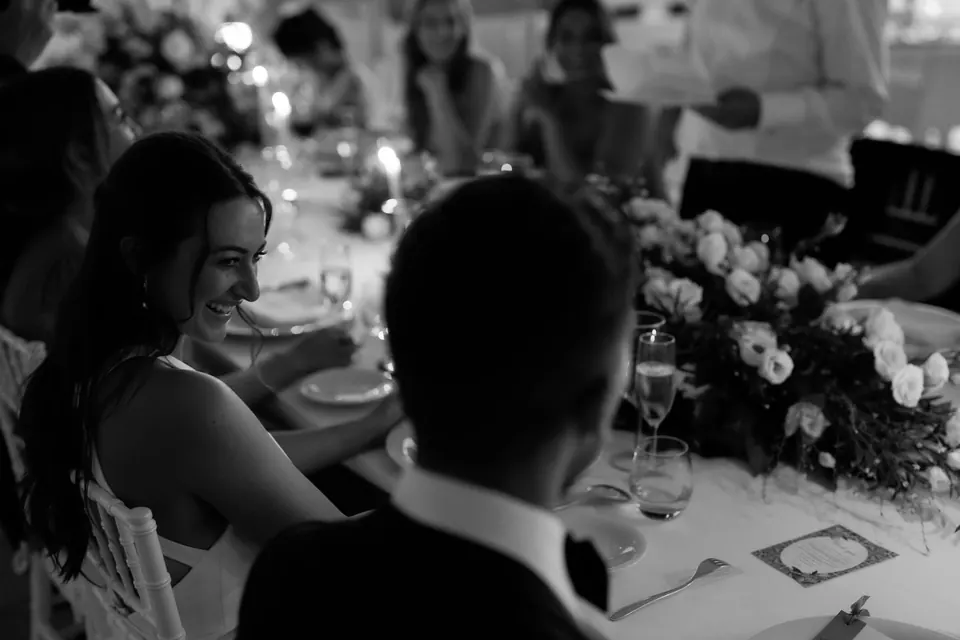Black and white photo of guests laughing at the dinner table.