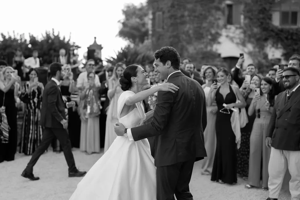 Foto in bianco e nero degli sposi che salutano gli invitati fuori dalla chiesa.