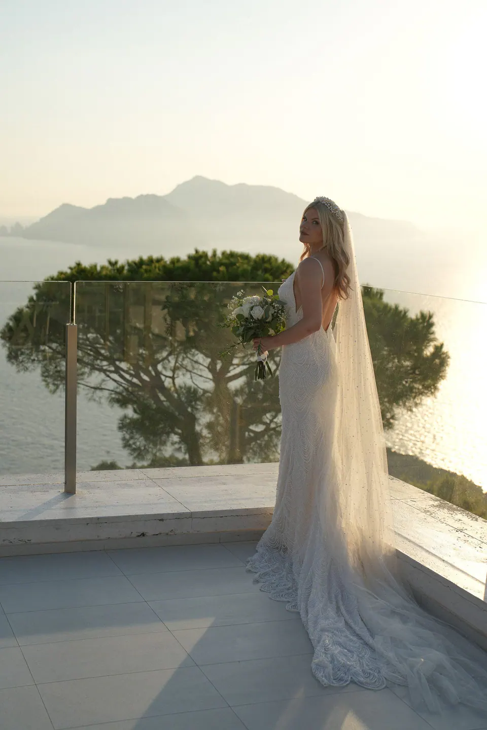 Bride alone on the terrace, Capri behind her at sunset