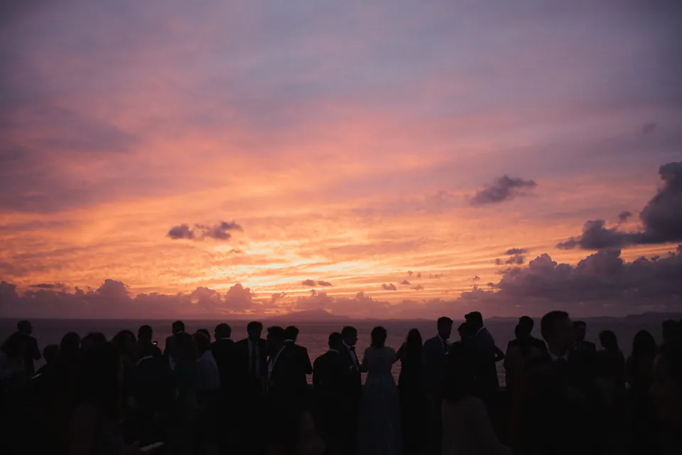 Invitati in controluce contro un tramonto rosa e arancione sul Golfo di Napoli al Castello Giusso.