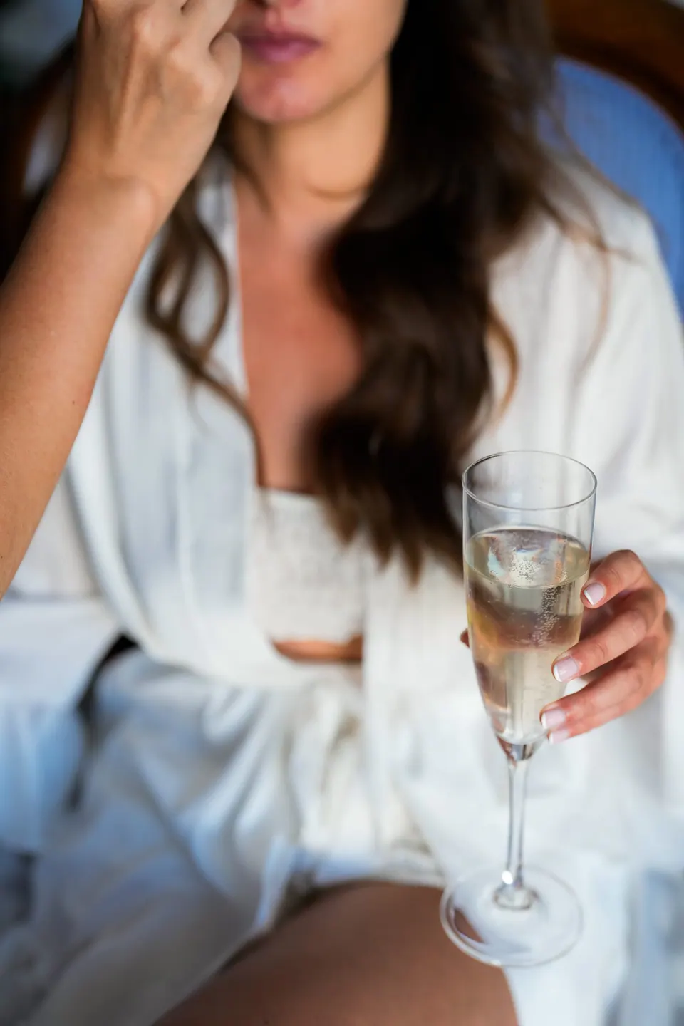 Bride holding a glass of champagne, smiling softly during cocktail hour.
