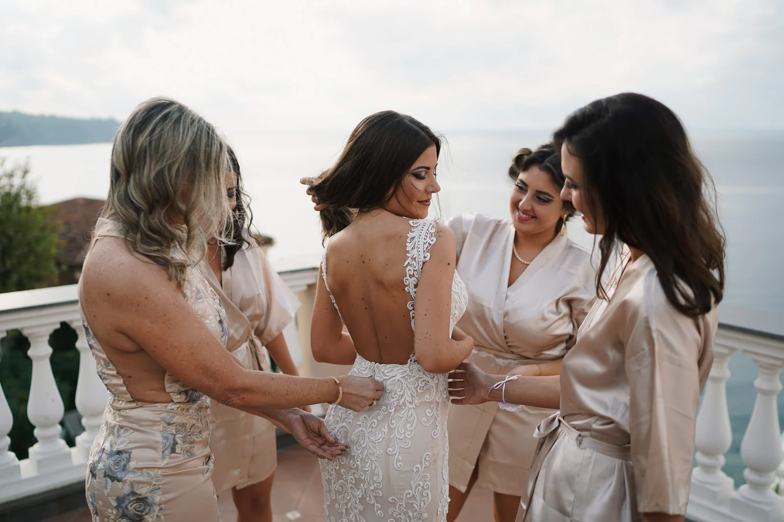 Bride and bridesmaids laughing together in their robes on the terrace of Hotel Corallo.