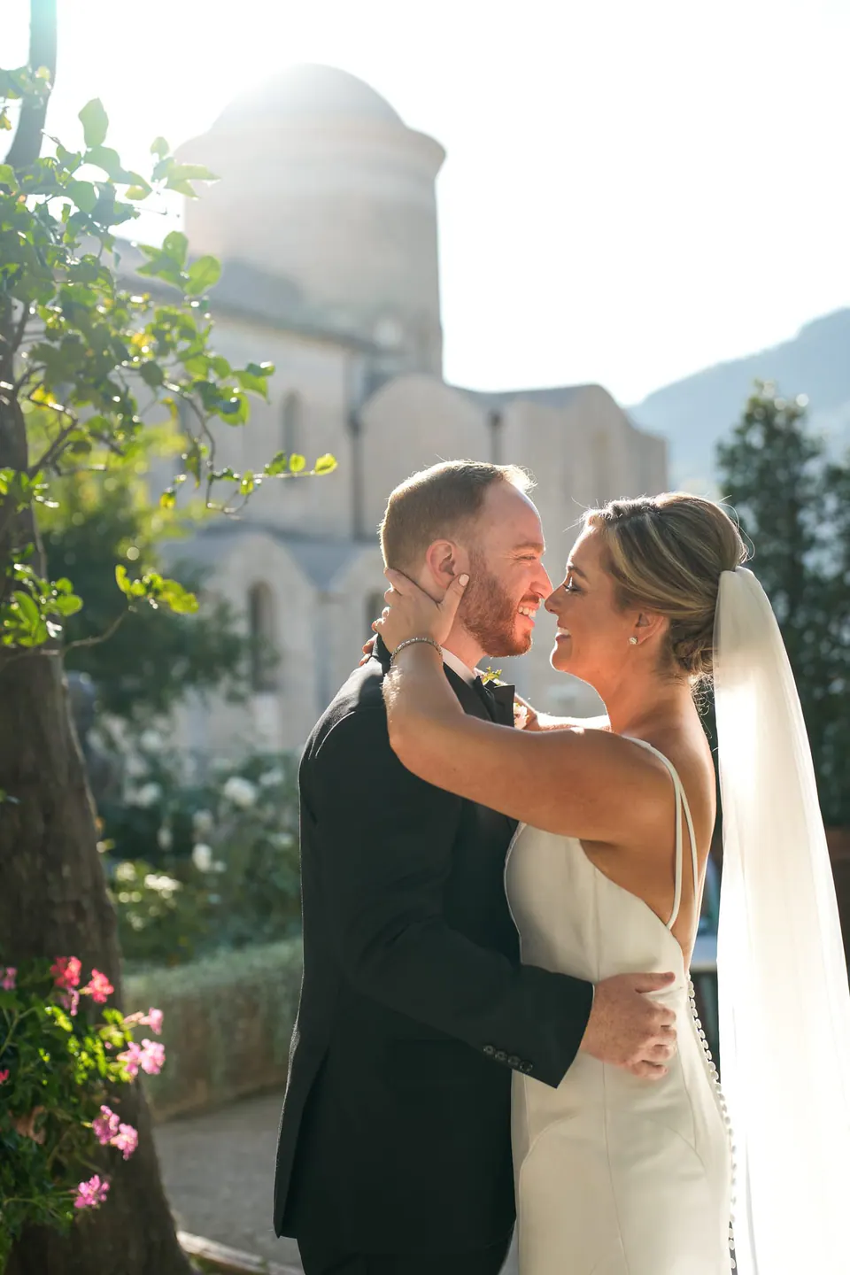 Bride and groom embracing with the stone towers of Ravello behind them