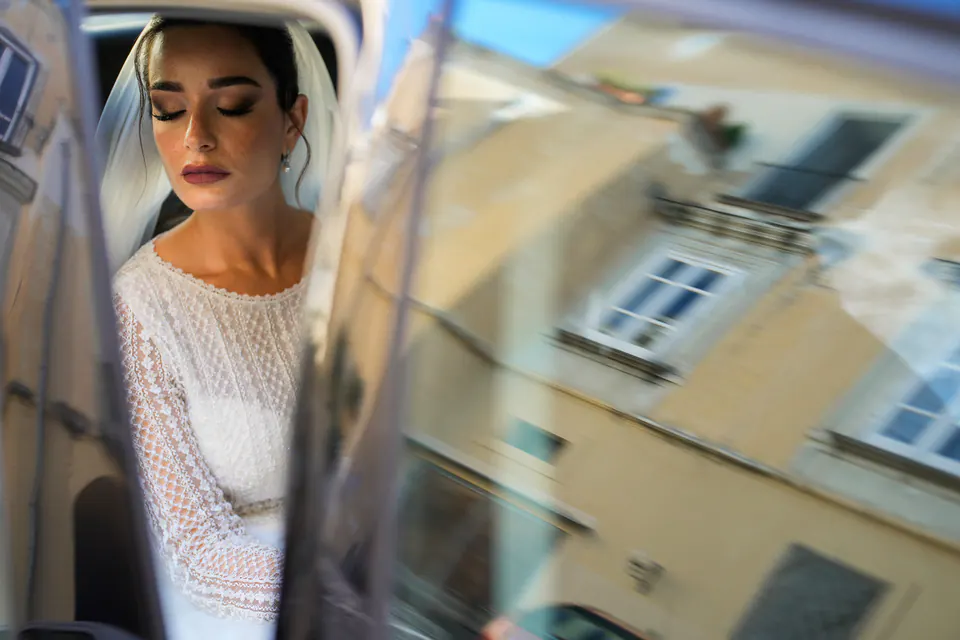 Bride reflected in the car window, a yellow Neapolitan building beside her.