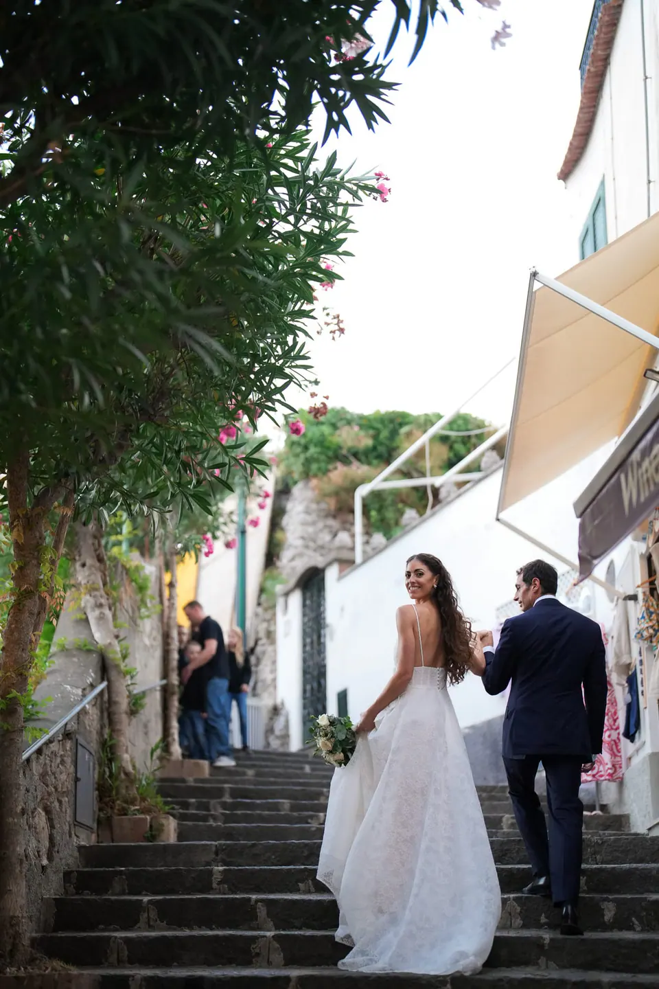 Bride and groom climbing a stepped lane in Amalfi.
