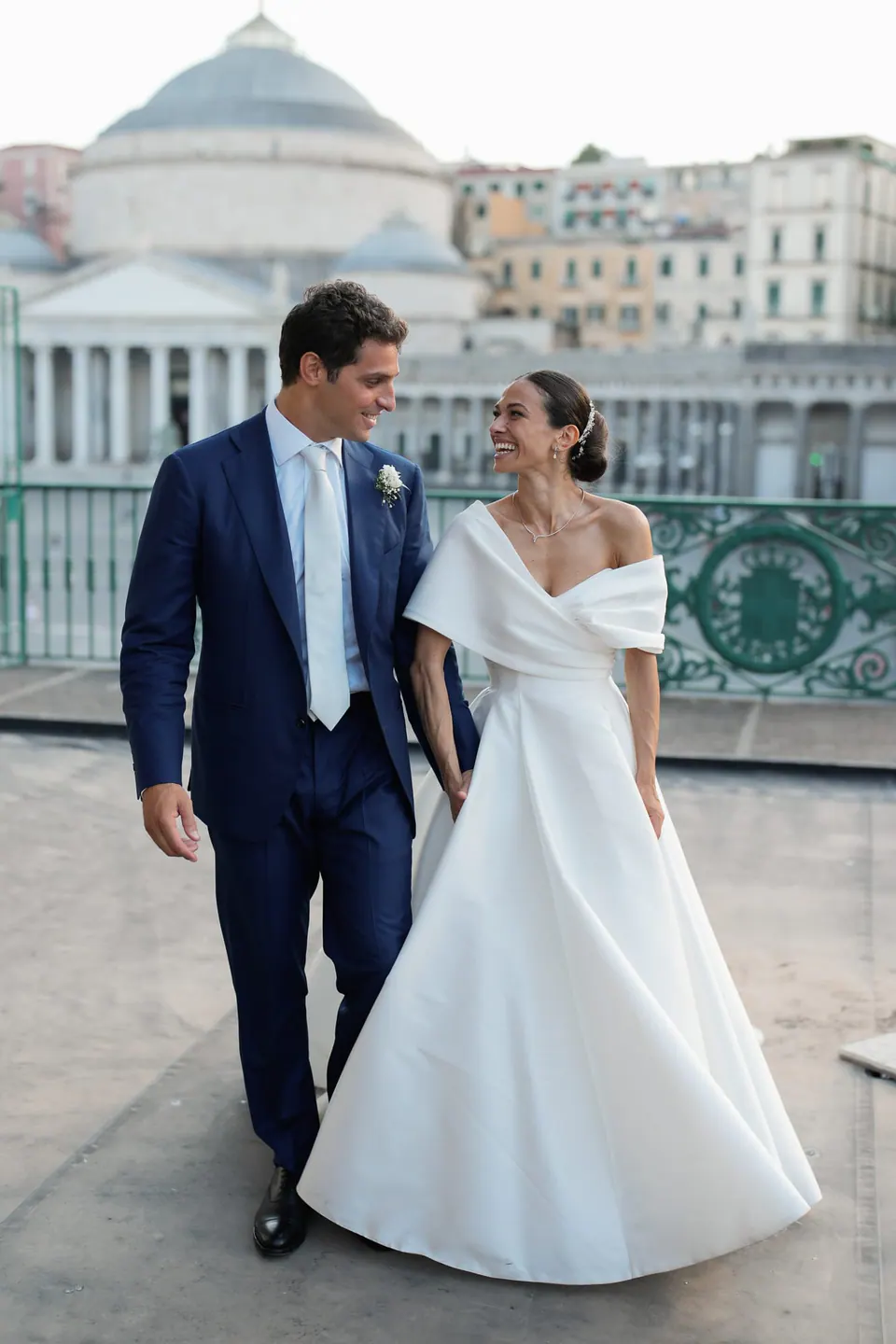 Bride and groom on a balcony in Naples, the dome of San Francesco di Paola behind them.
