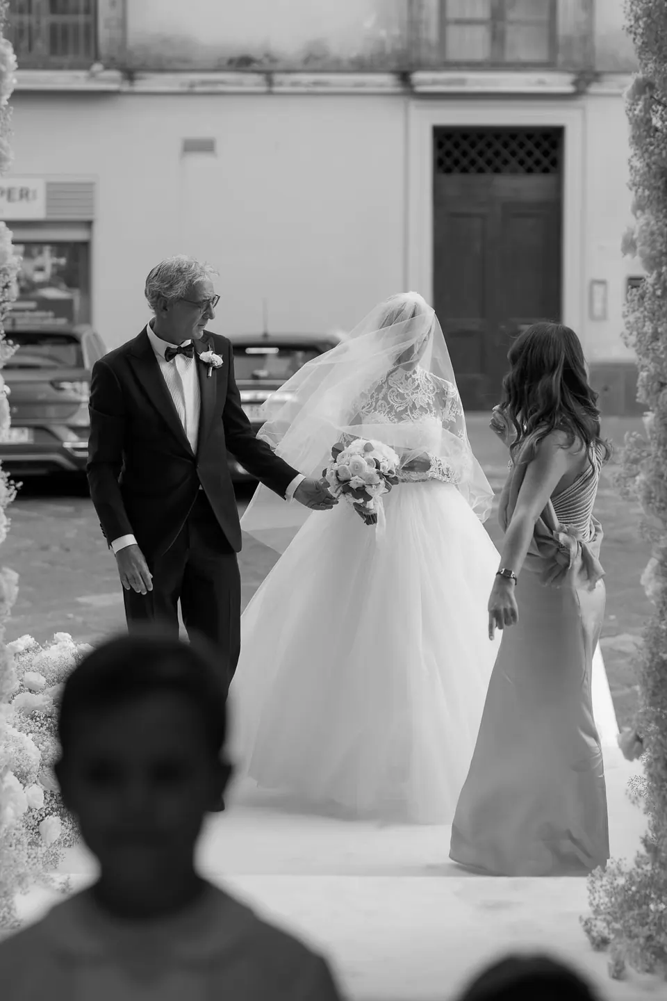 Black and white photo of the bride walking with her father