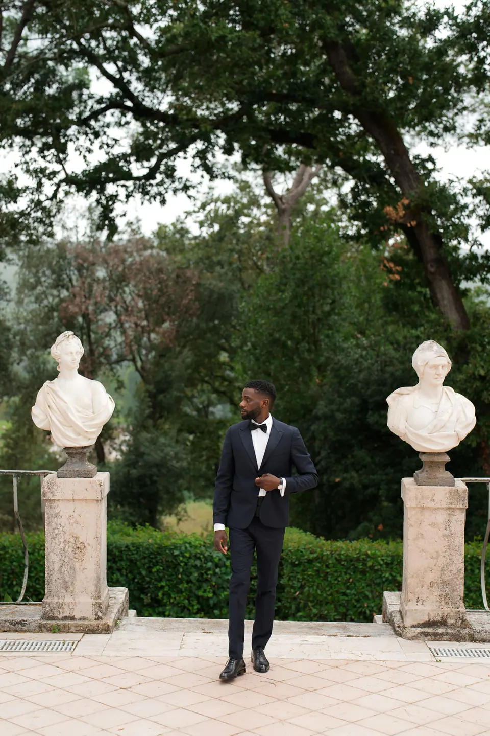 El novio entre estatuas de mármol en una boda italo-nigeriana en Villa Ortensia D’Avalos.