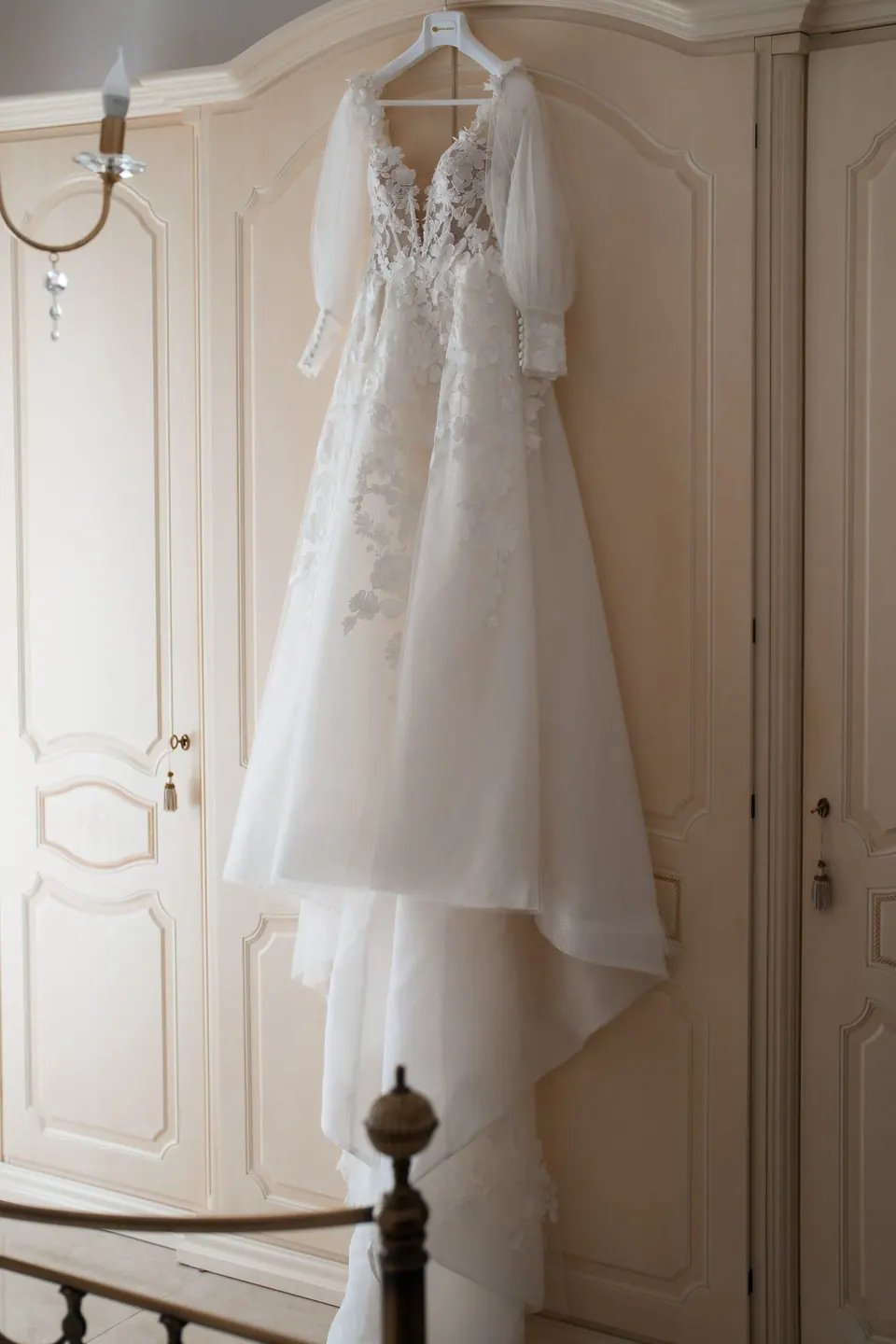 Wedding dress hanging on a wall in warm light.