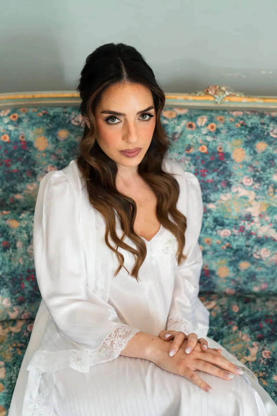 Retrato de la novia en bata en un sofá de flores.