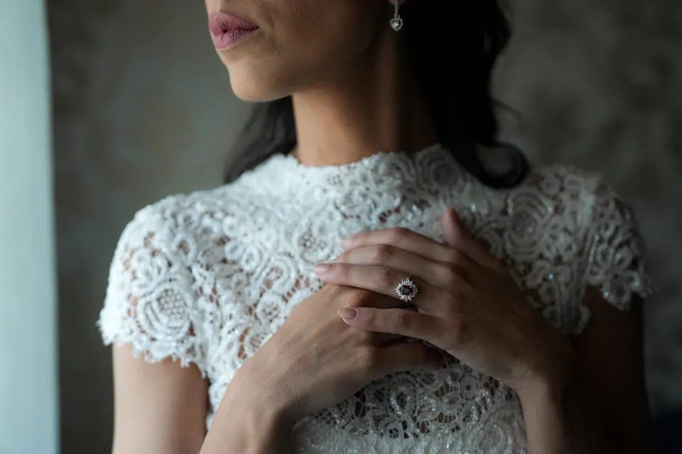 Bride touching the lace collar of her gown.