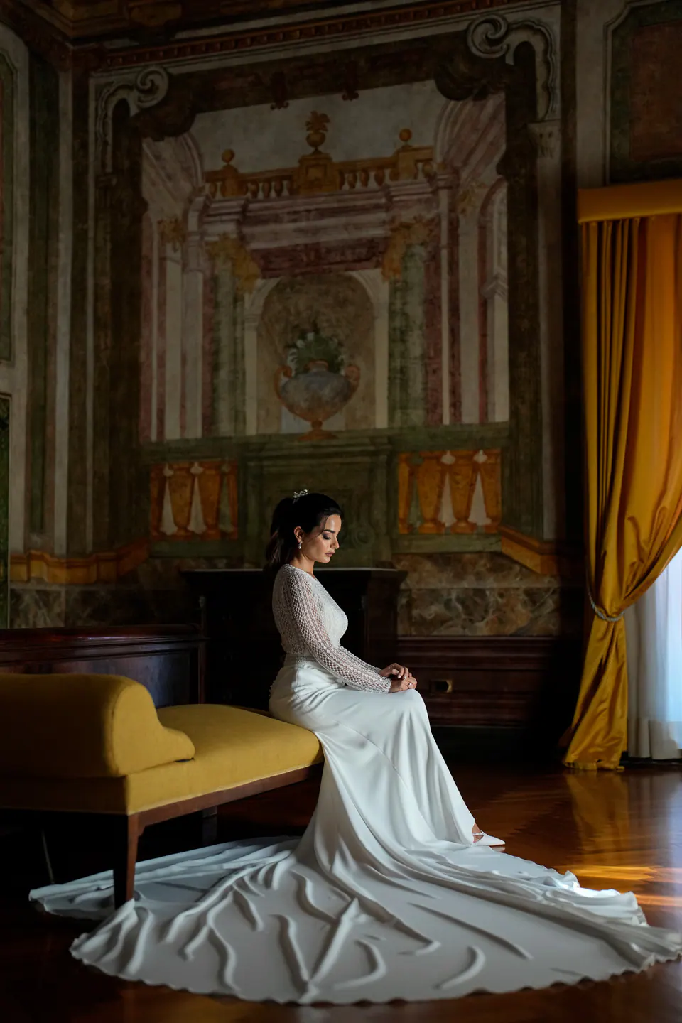 Bride seated in a royal palace hall, train flowing across marble floors.
