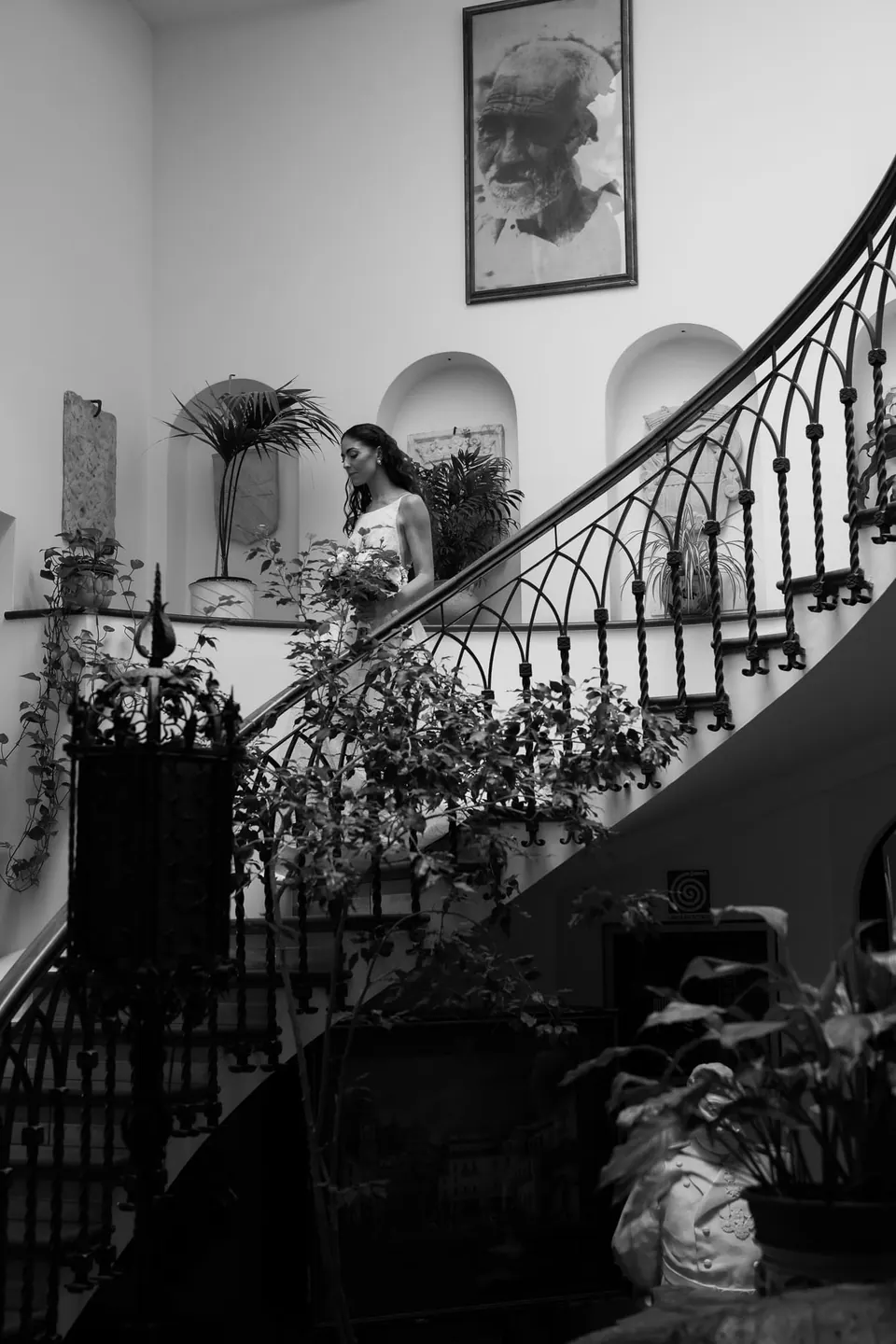 Black and white photo of the spiral staircase in the hotel, the bride at the top.
