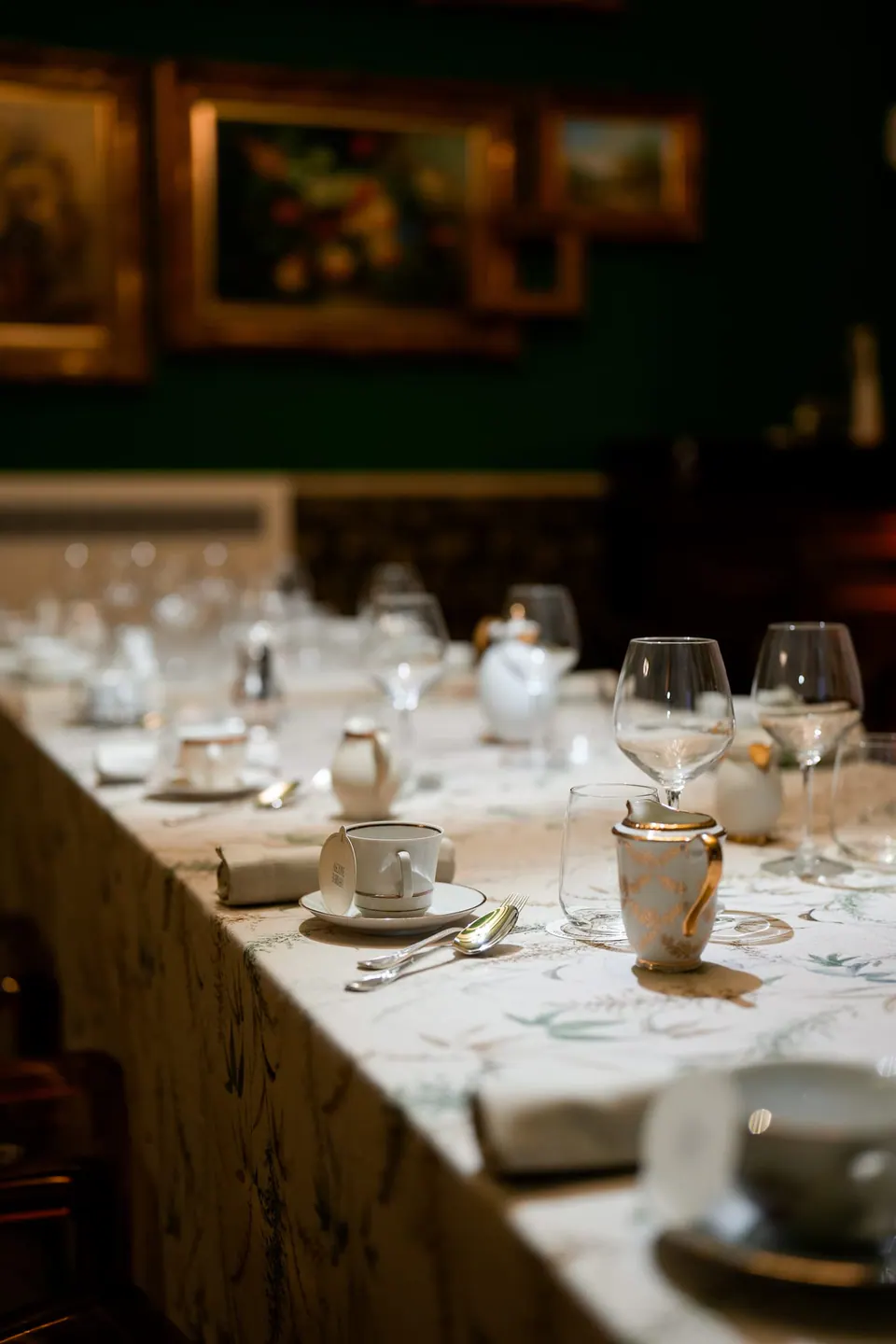 Mesa de la cena en una sala oscura con cuadros antiguos.