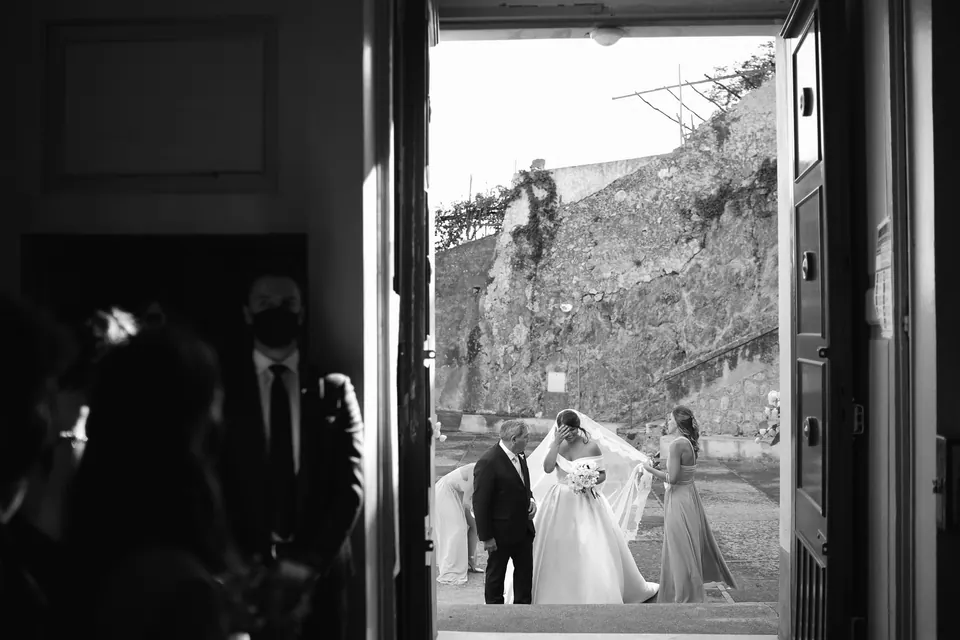 Black and white photo through a doorway of the couple on a lane above the coast.