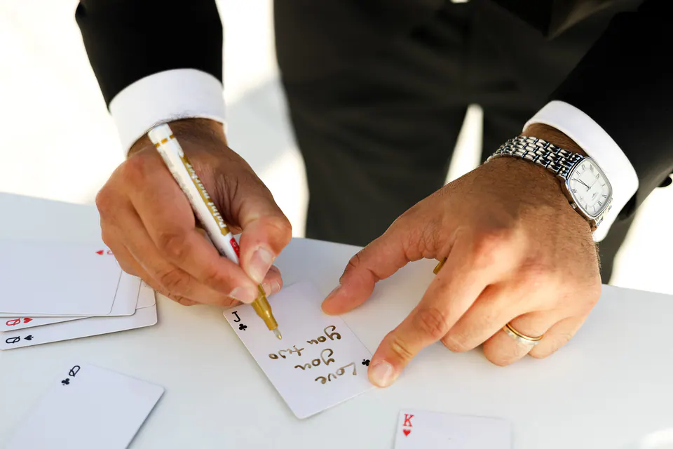 Un invité écrit un message sur une carte à jouer, le livre d’or du couple.