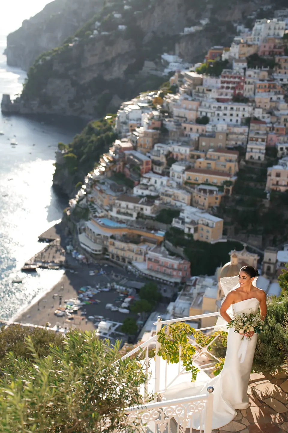 Bride on the terrace above the town, flowering plants around her.
