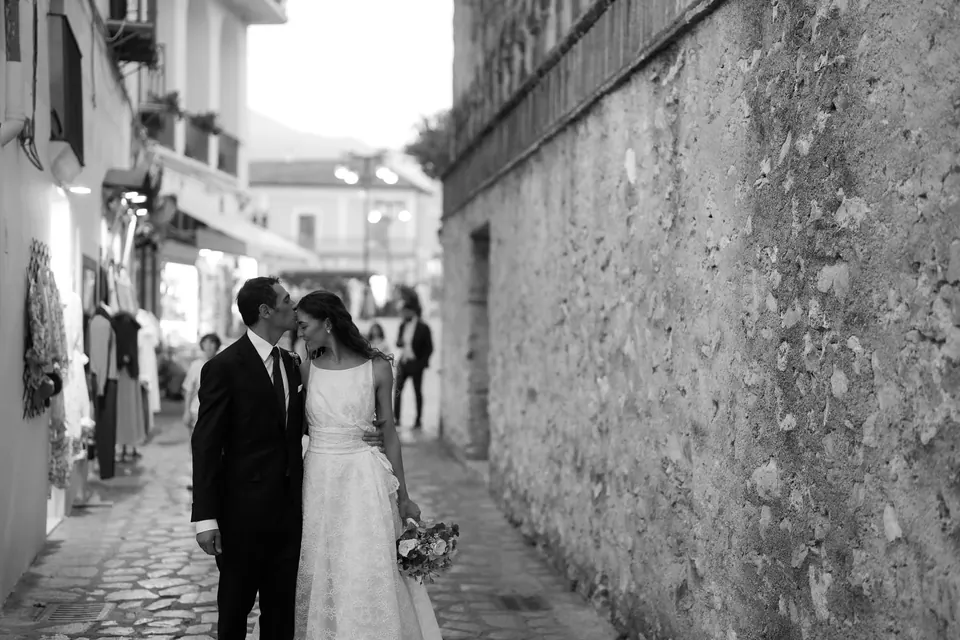 Black and white photo of the couple kissing in a narrow stone lane.