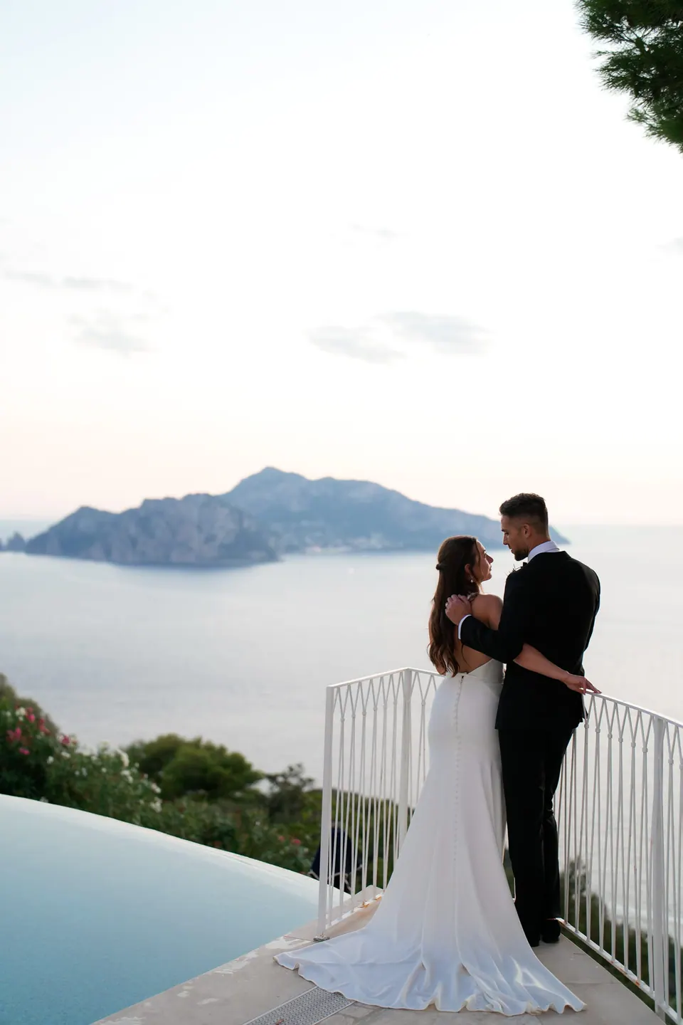 Bride and groom at the pool railing of Relais Blu, Capri across the sea.