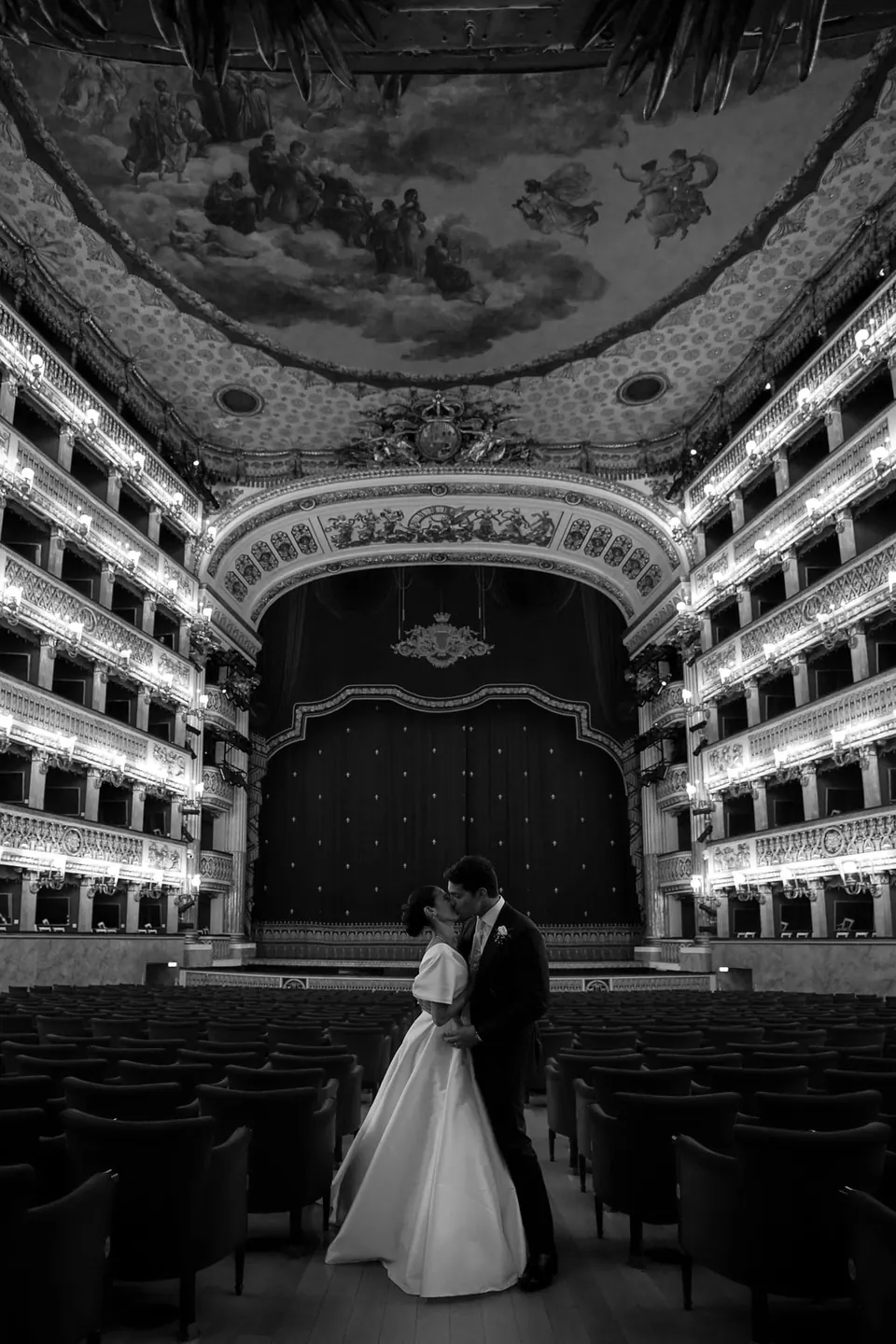 Foto in bianco e nero degli sposi sul palcoscenico del Teatro San Carlo, i palchi alle spalle.