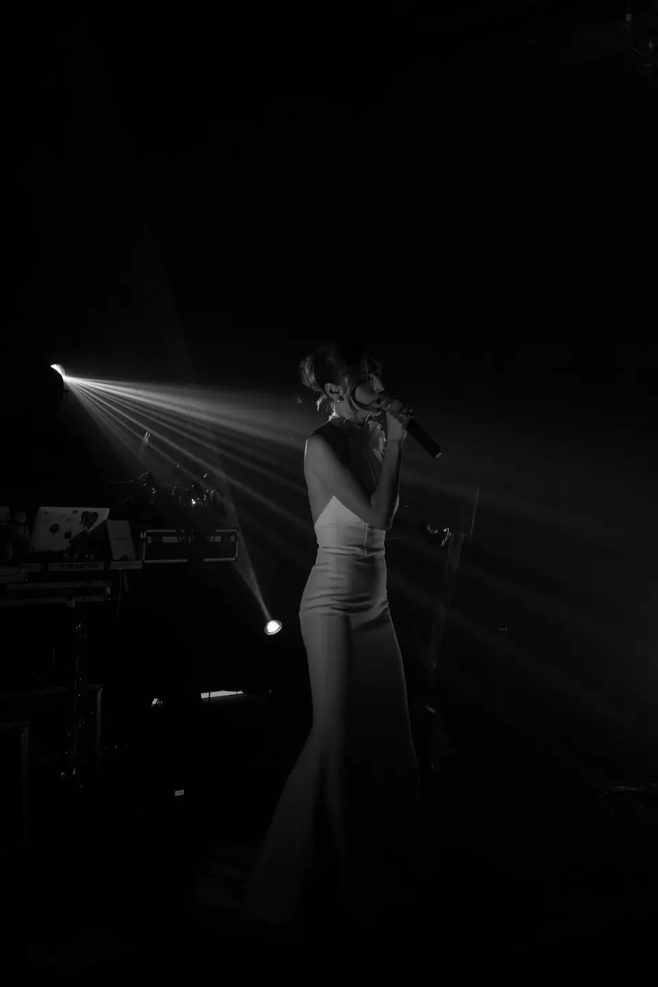 Immagine in bianco e nero della sposa che canta al microfono in un fascio di luce del palco.