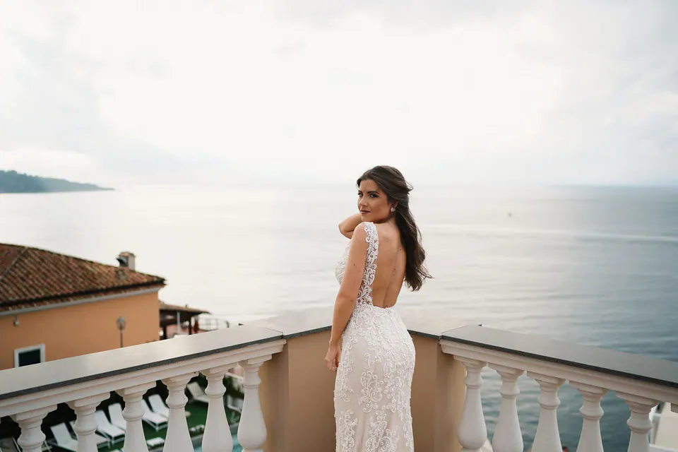 Bride in her gown standing on the terrace above the sea.