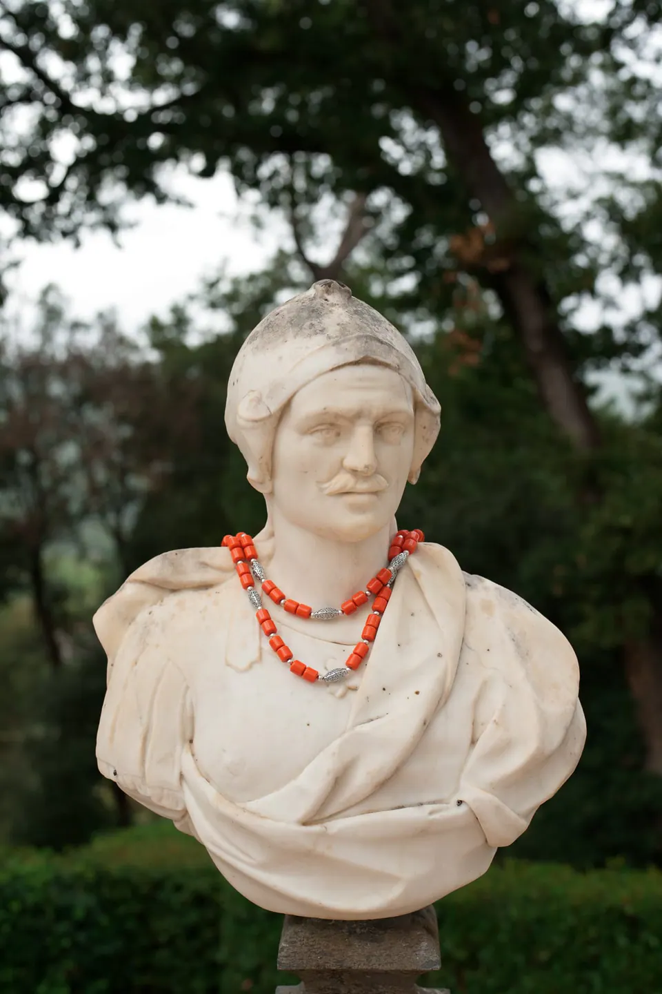 Busto de mármol en los jardines de Villa Ortensia D’Avalos con un collar de cuentas de coral, detalle de una boda italo-nigeriana cerca de Caserta.