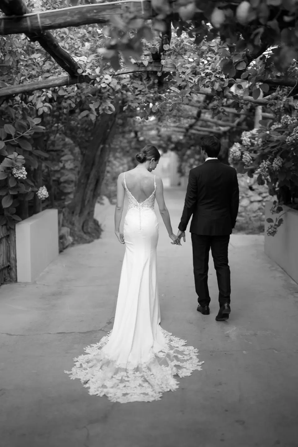 Black and white photo of the couple walking away under the pergola.
