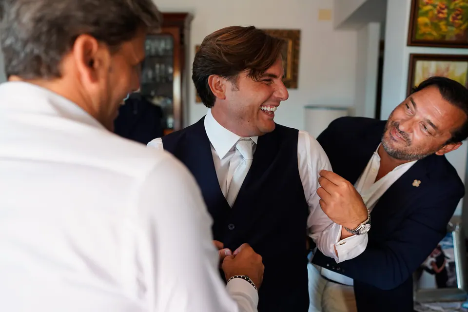 Groom and his friends laughing together during the celebration, relaxed and cheerful mood.