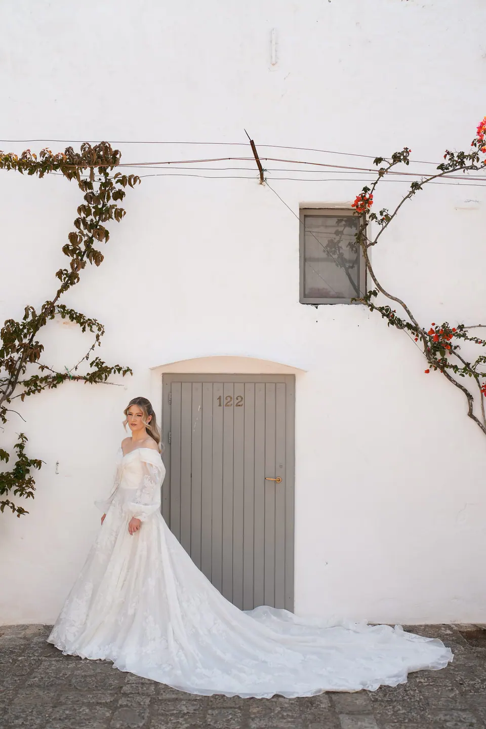 La novia camina por un sendero de piedra bajo el sol mediterráneo.