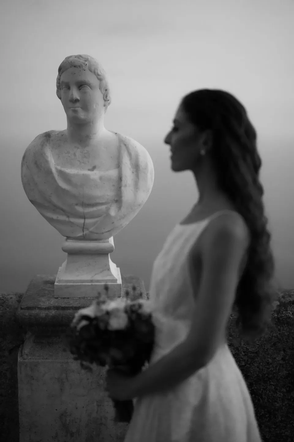 Black and white photo of the bride beside a marble bust at Villa Cimbrone.