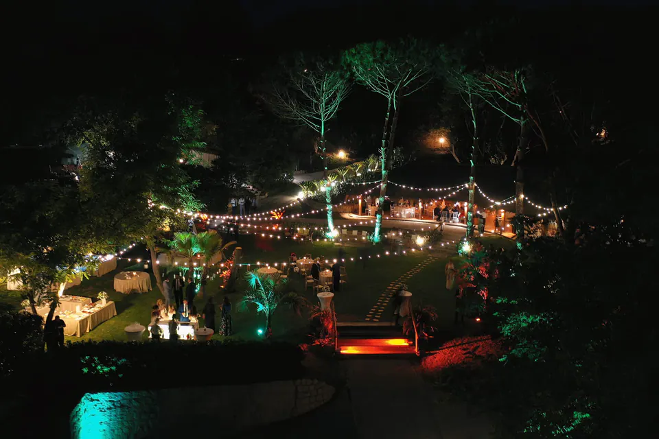 Night view of the illuminated wedding reception, warm lights reflecting over the sea.