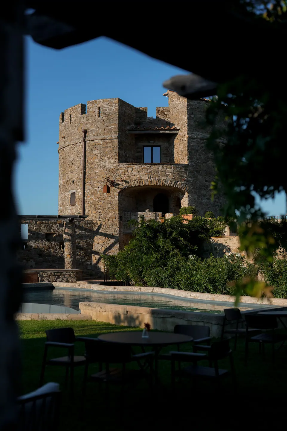 Torre del castello vista attraverso una finestra in ombra, cielo azzurro oltre.