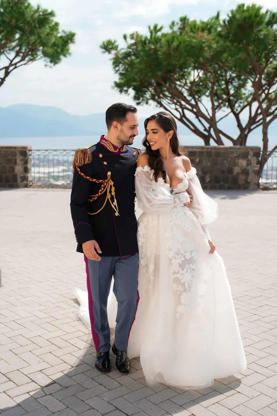 Groom in dress uniform and bride on the terrace of Villa Scalera, umbrella pines and the gulf behind them.