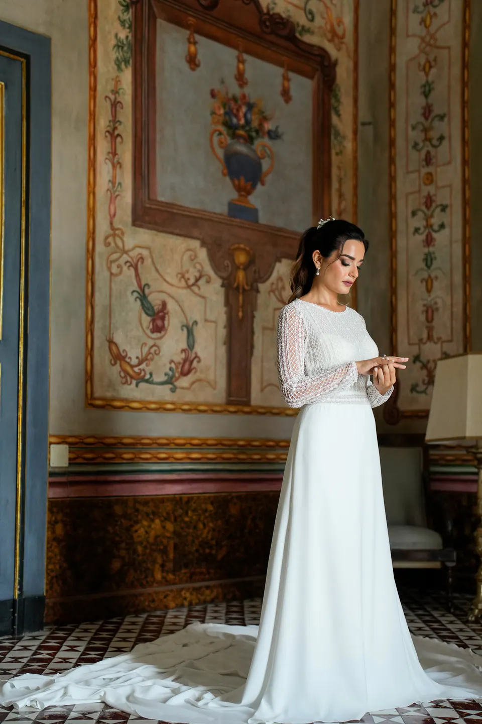 Bride posing in a palace hallway, her gown trailing behind her on marble floors.