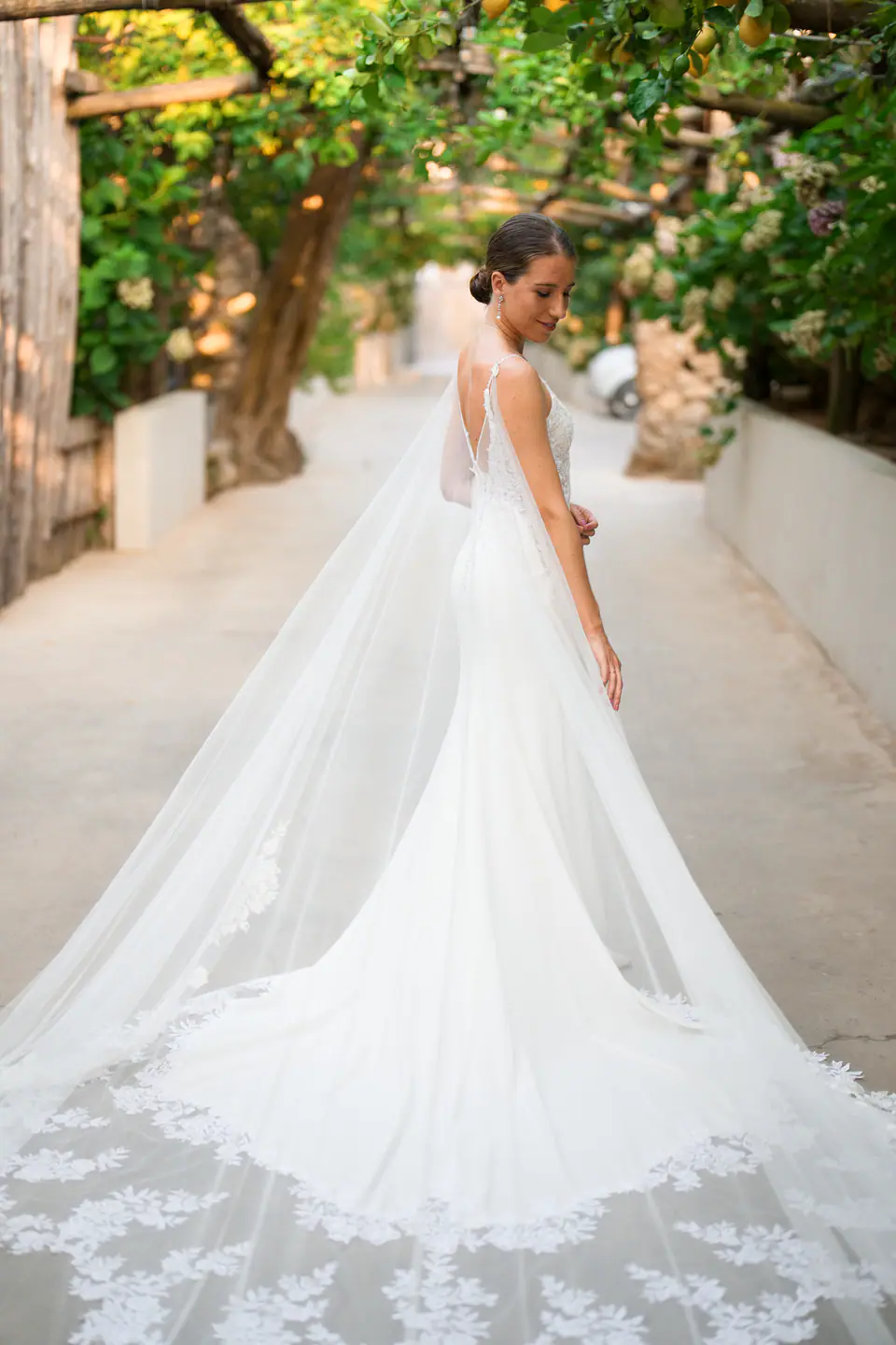 Bride in a long lace train under a lemon pergola.