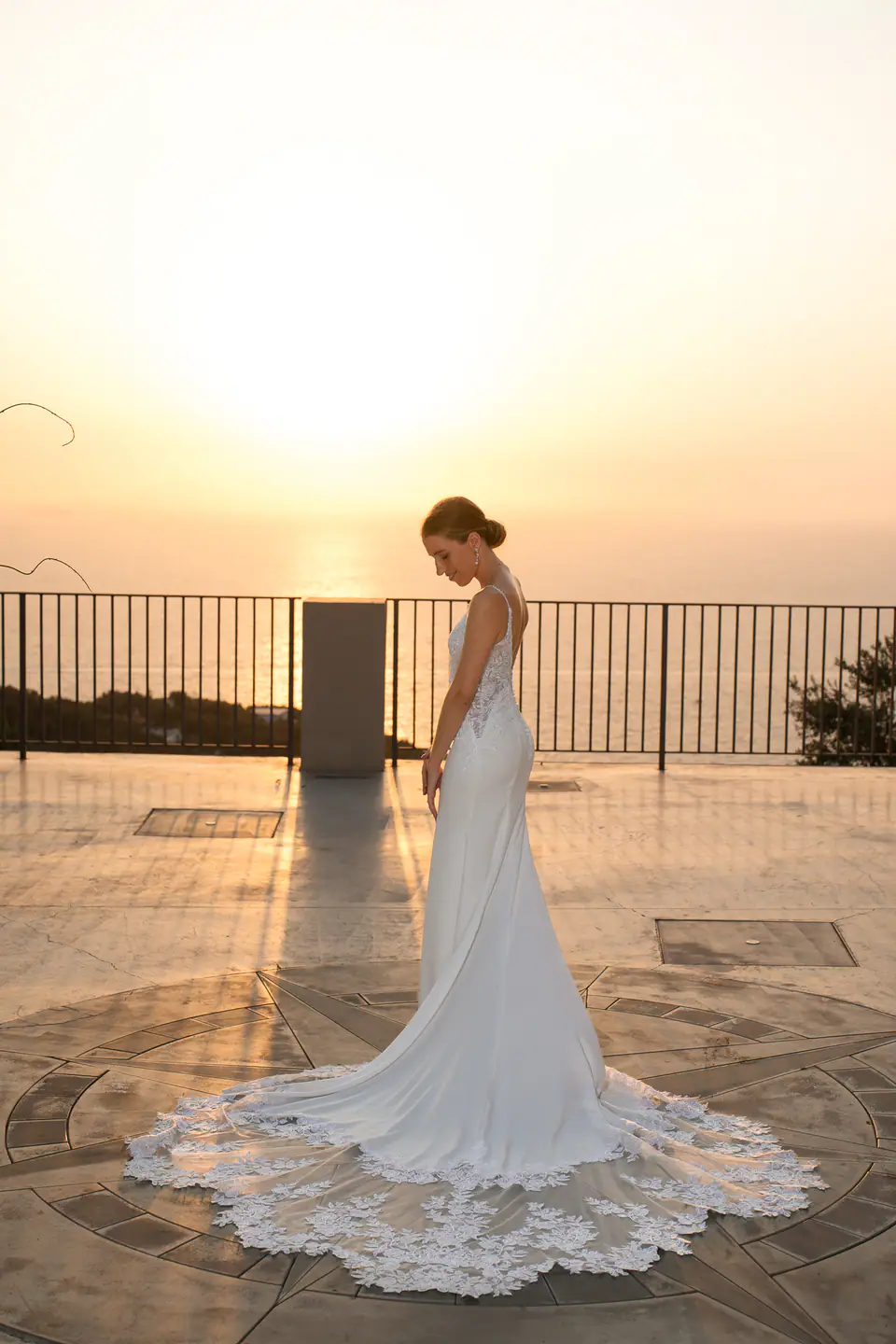 Bride on the terrace at sunset, her train spread on the floor.