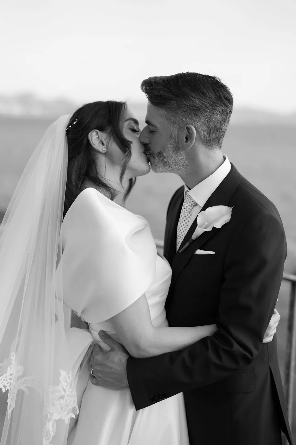 Black and white photo of bride and groom kissing