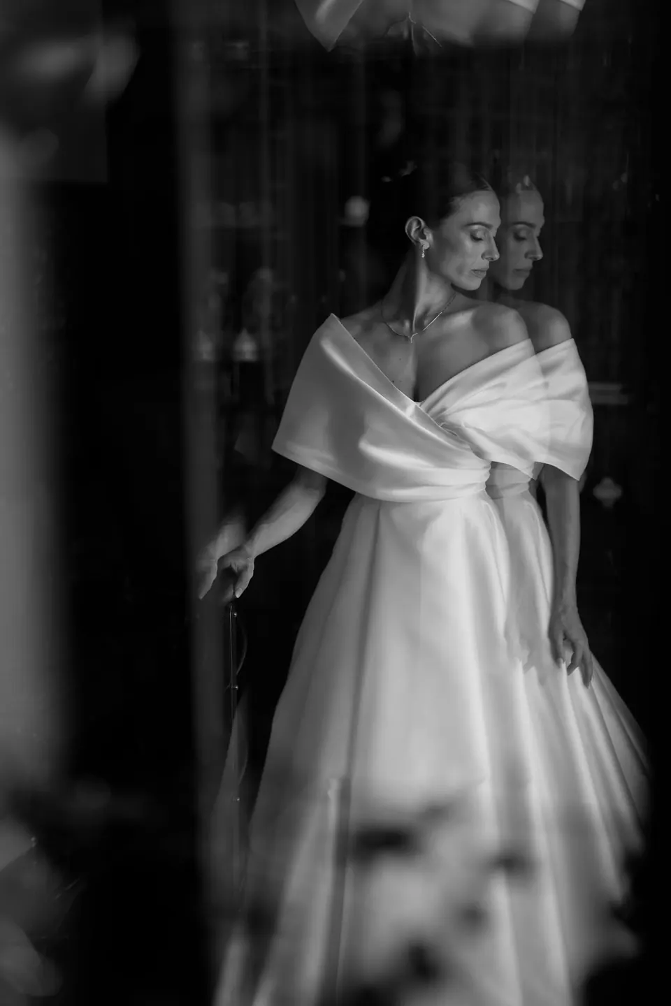 Foto in bianco e nero della sposa tra tende scure.
