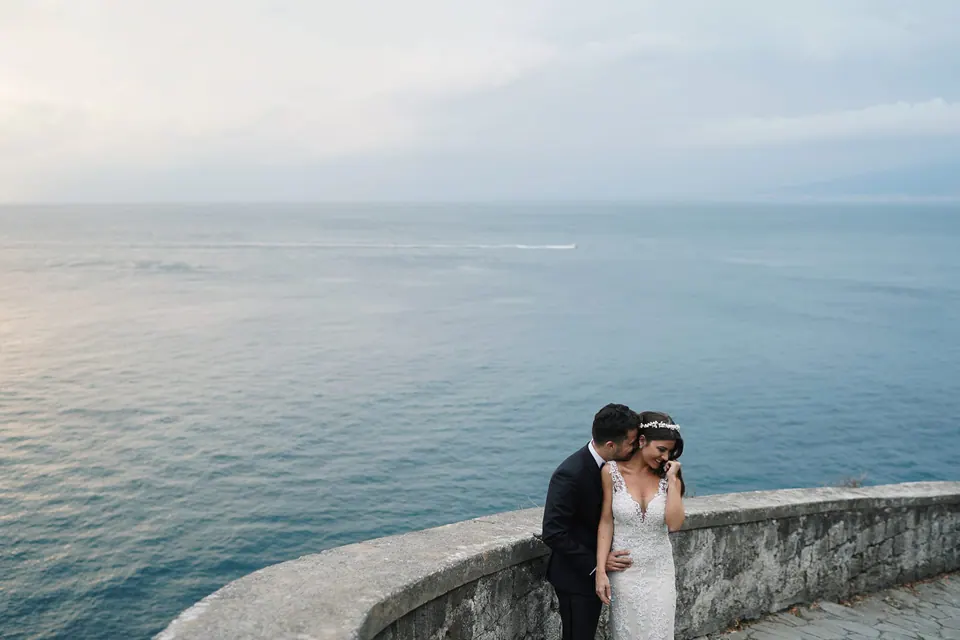 Bride and groom on the curving sea wall, the Gulf of Naples around them.