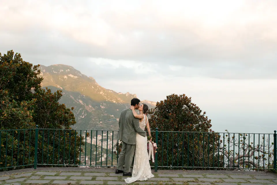 Couple at a railing above the coastline and the sea at dusk.