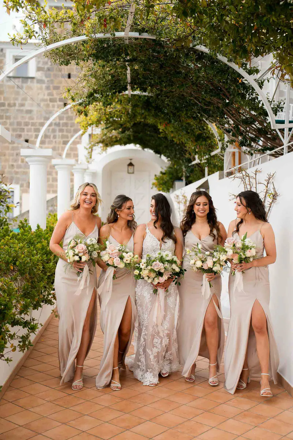 Damigelle in abiti color champagne con bouquet bianchi sulla terrazza della villa.