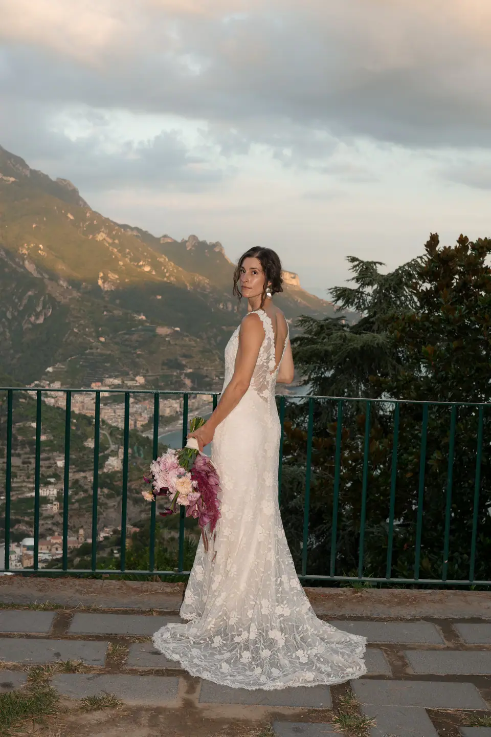 Bride on a terrace at sunset, the mountains of the coast behind her.