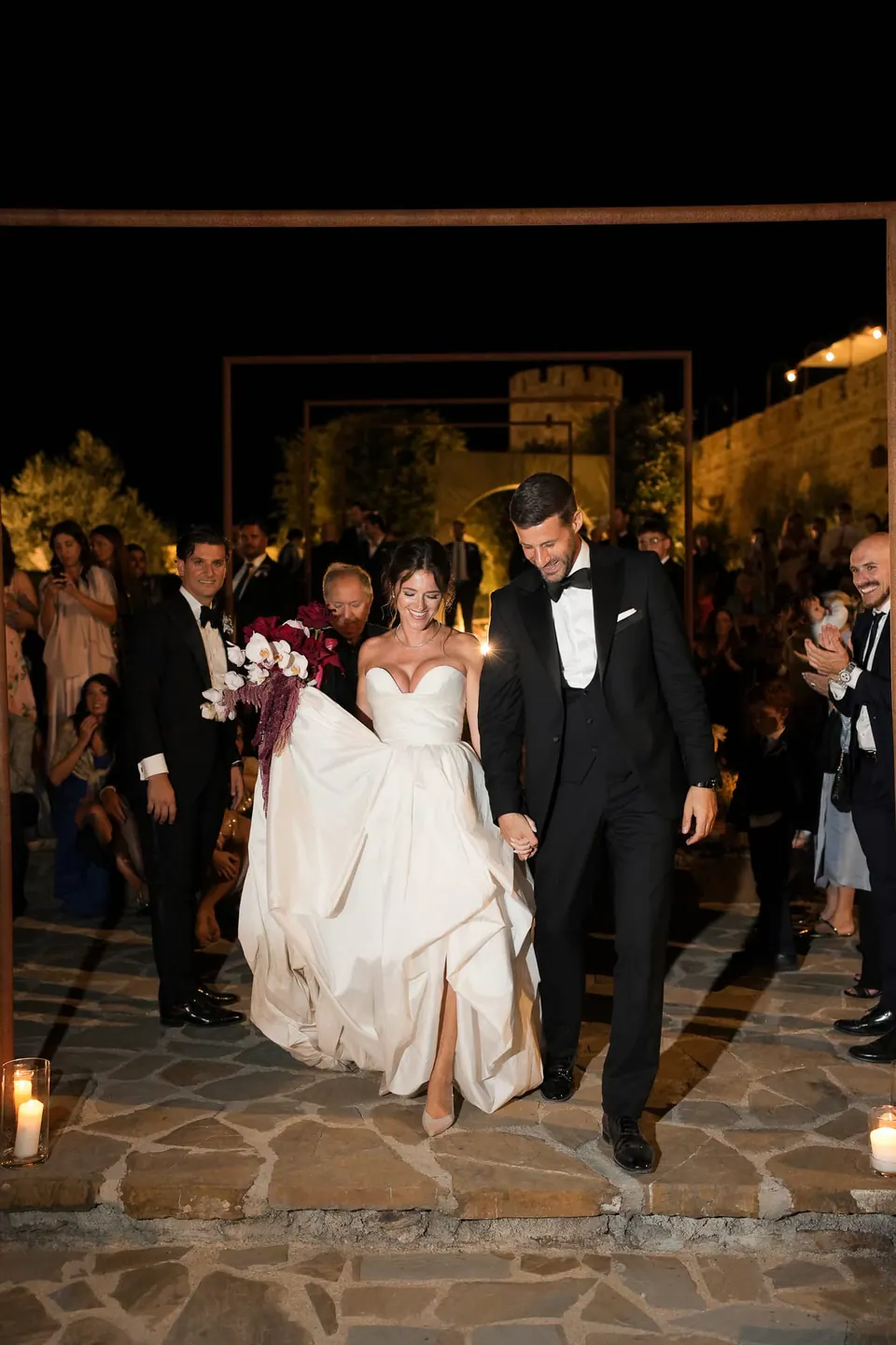 Ingresso degli sposi di sera tra gli invitati che applaudono.