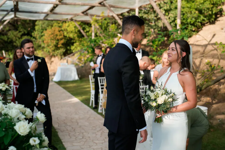 Bride and groom at the altar under the garden pergola, guests watching.