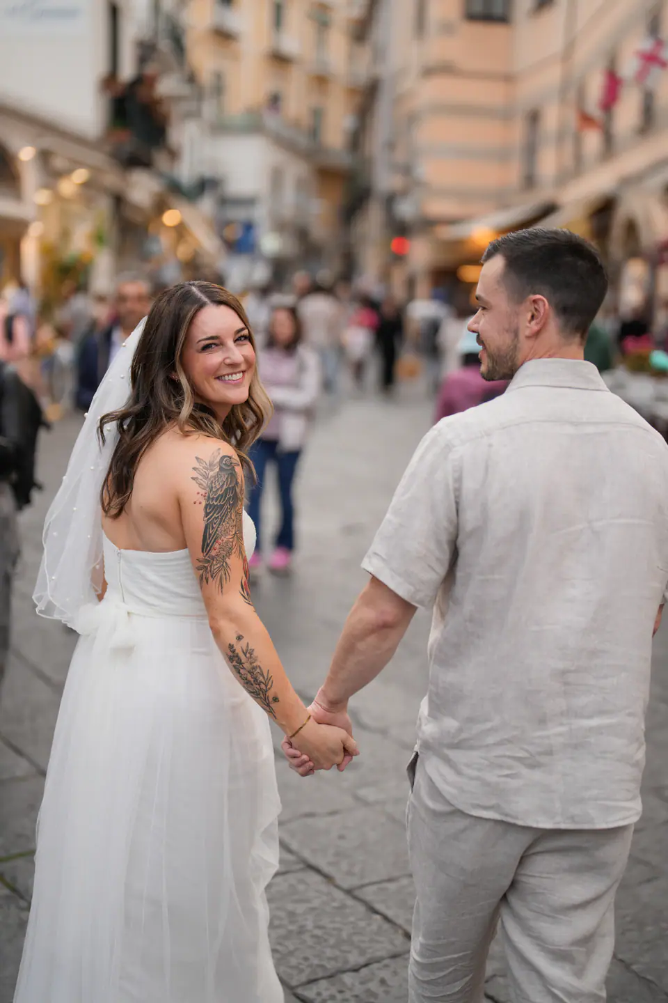 Bride smiling over her shoulder as she leads the groom through the lanes of Amalfi.