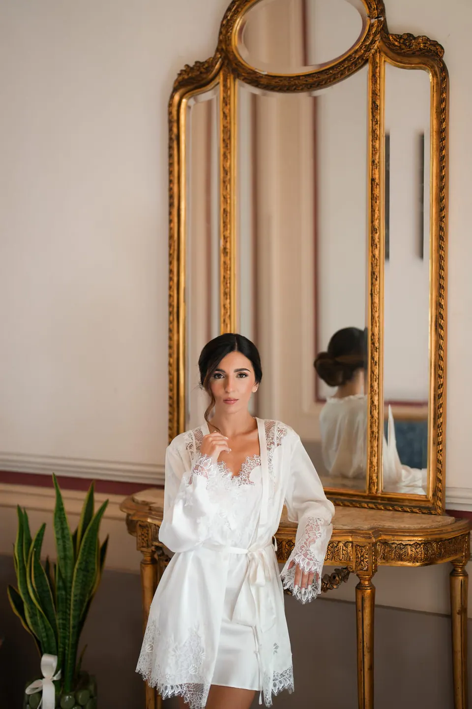 Bride in her robe beside a gilded mirror