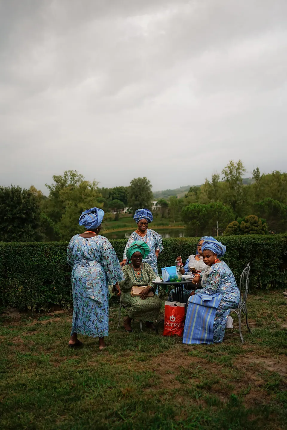 Grupo de invitados con traje tradicional azul reunidos para la ceremonia al aire libre.