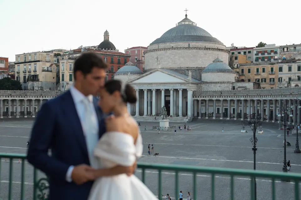Sposi su un balcone affacciato su Piazza del Plebiscito al tramonto.